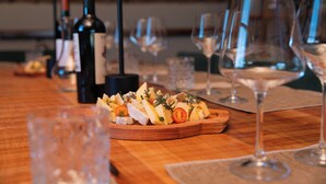 Une table en bois, sur laquelle on trouve un plateau de fromages, des verres à vin et des bouteilles.