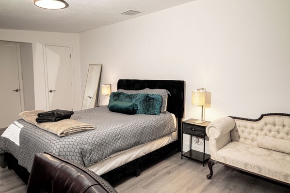 Une chambre bien rangée, avec un lit, des tables de chevet, une chaise et un miroir.