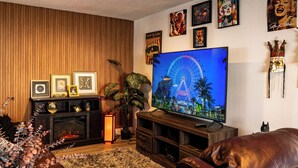 A living room with a television, framed pictures, and a plant. - Modern & Homely Entire House Orlando. Key Location! (Orlando)