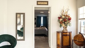 A room with a bed, a mirror, a green chair, a wooden cabinet with a globe, and a floral arrangement. - Modern & Homely Entire House Orlando. Key Location! (Orlando)