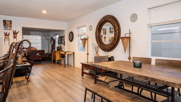 A spacious living room with a wooden dining table, benches, and a large mirror. There is a fireplace, a bookshelf, and a door leading to another room. - Modern & Homely Entire House Orlando. Key Location! (Orlando)
