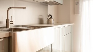 A modern kitchen with a stainless steel sink, a kettle, and white cabinetry.