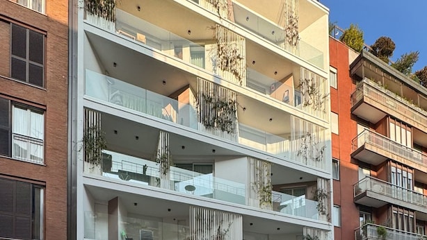 A multi-story residential building with balconies, some with plants.