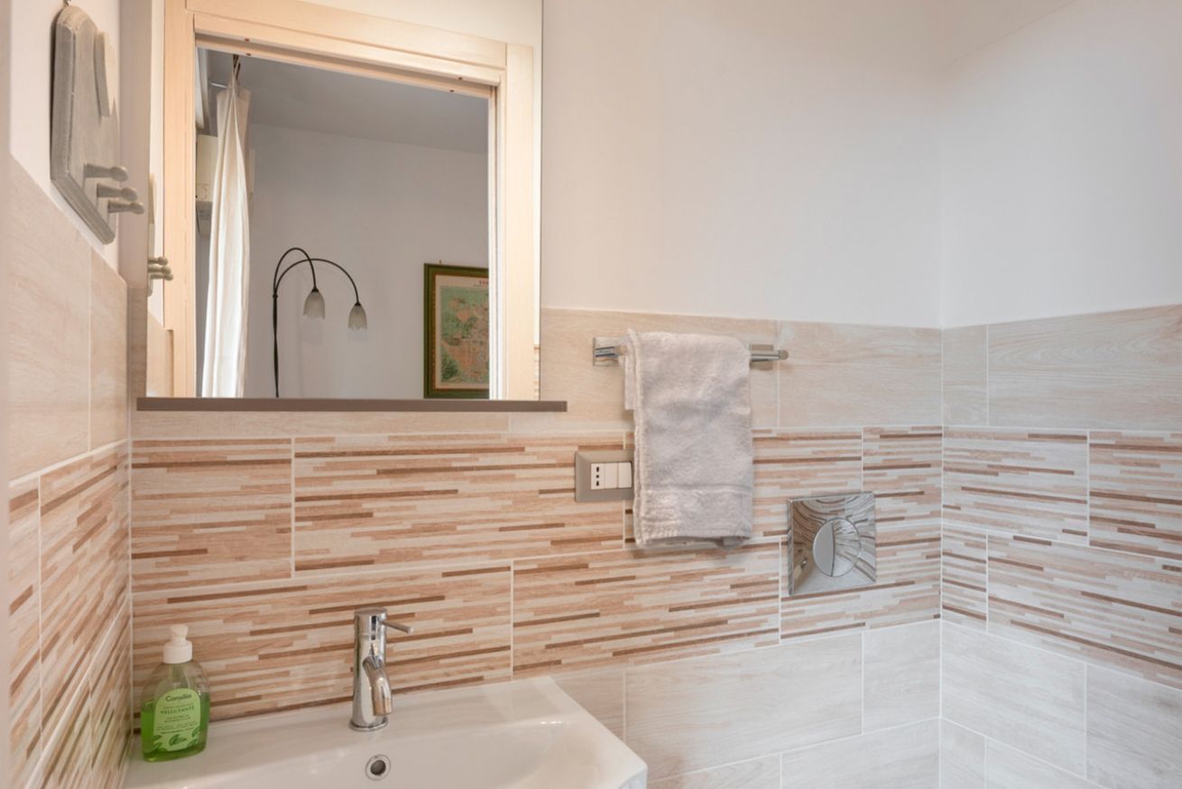 A bathroom with a sink, mirror, and towel rack.