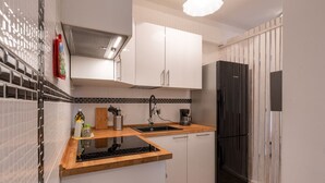 A compact kitchen with white cabinets, a black refrigerator, a wooden countertop, and a tiled backsplash. - Ancient Roman Style - 7th Floor - Exclusive Apt (Roma)