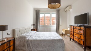 A bedroom with a bed, dresser, TV, and a window with curtains. - Ancient Roman Style - 7th Floor - Exclusive Apt (Roma)