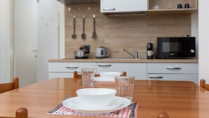 A dining table with a white bowl, plates, and cutlery, set in a modern kitchen with wooden cabinets and a microwave. - Da Vinci - Exclusive Apartment - Navigli (Milano)
