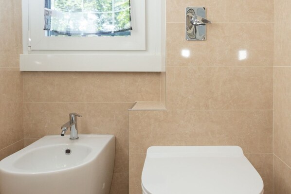 A bathroom with a sink, toilet, and a window.