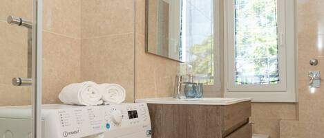 A modern bathroom with a washing machine, a wooden cabinet, a sink, and a toilet.
