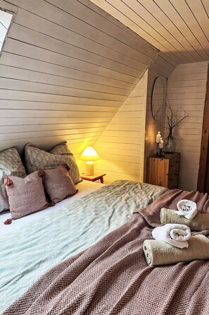 A cozy bedroom with a bed, pillows, a bedside table with a lamp, and a nightstand with a vase. - Studenec by Interhome (Studenec)