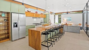 A modern kitchen with a central island, bar stools, and a refrigerator.