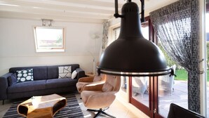 A modern living room with a dark sofa, a light-colored armchair, and a unique wooden coffee table. - Gaai | Prachtig nabij natuur (Zwiggelte)