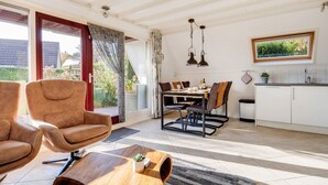 A spacious living room with a large window, a dining area with a table set for four, and a kitchen with white cabinets. - Gaai | Prachtig nabij natuur (Zwiggelte)