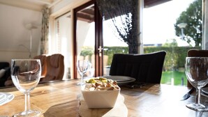 A dining table with a bowl of nuts and two wine glasses, a chair, and a window with a view of greenery. - Gaai | Prachtig nabij natuur (Zwiggelte)