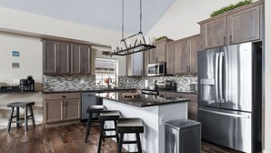 A modern kitchen with a central island, stainless steel appliances, and dark wood cabinetry. - Lake Escape: Views, Hot Tub, Game Room & Pools (Hollister)
