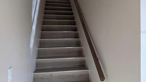 Una escalera de madera con escalones y barandilla, que conduce a un piso superior.