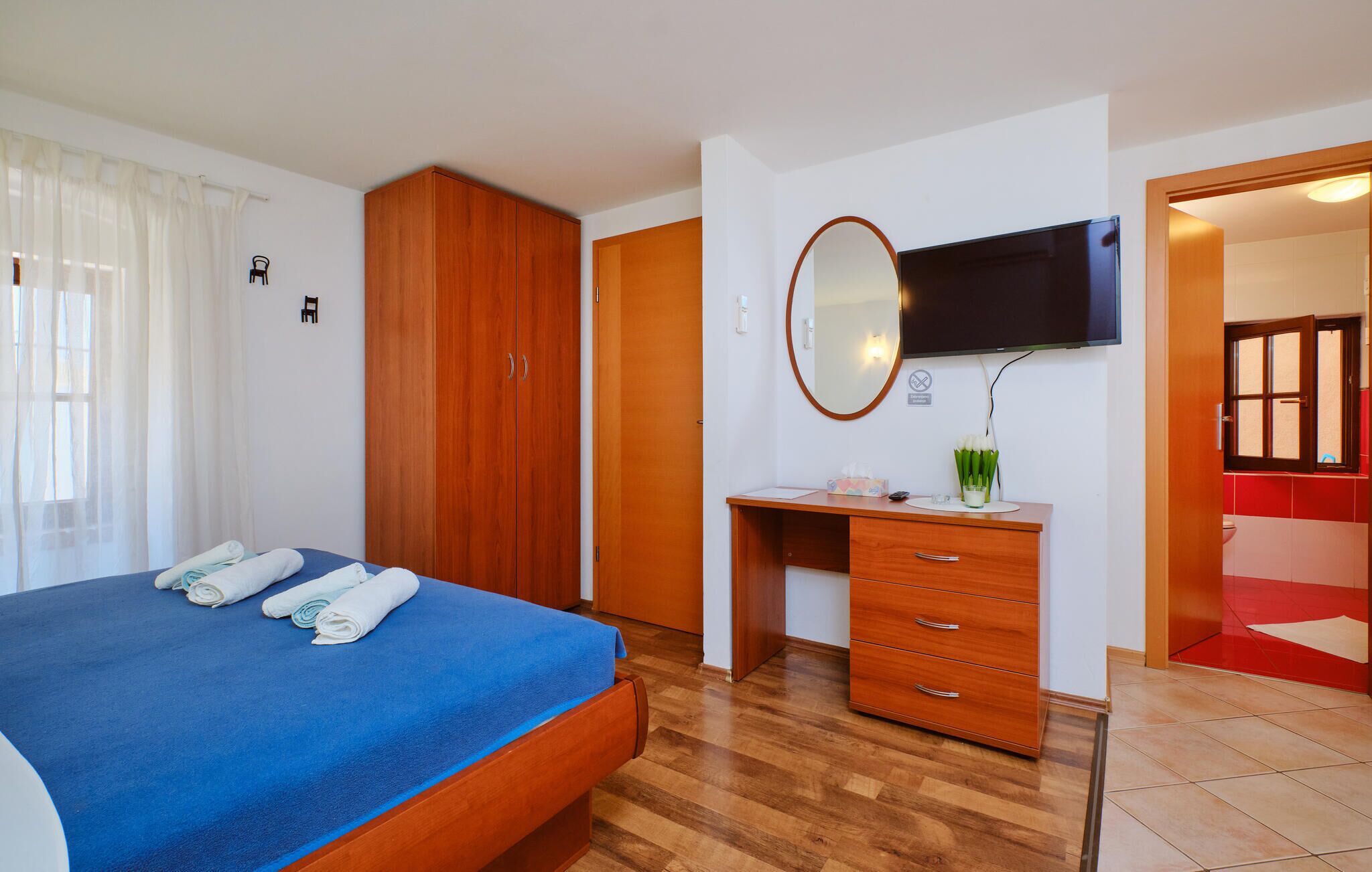 Habitación de hotel con cama, armario de madera, escritorio y televisor.