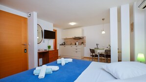 Une chambre d’hôtel comprenant un lit, un bureau avec un téléviseur à écran plat, une kitchenette et un coin repas.