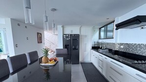 Una cocina moderna con encimera negra, armarios blancos y un refrigerador de acero inoxidable.