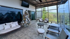 Un interior moderno con un gran ventanal, un árbol de Navidad, un sofá y una zona de comedor.