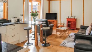 Une cuisine moderne avec un coin repas, un téléviseur et un salon comprenant un canapé et un meuble rouge.
