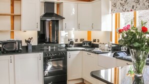 Une cuisine moderne avec des meubles blancs, une cuisinière noire et un four à micro-ondes.