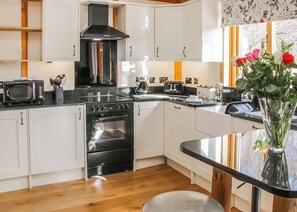 Une cuisine moderne avec des meubles blancs, une cuisinière noire et un four à micro-ondes.