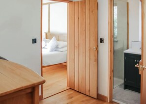 Eine Holztür, die zu einem Schlafzimmer mit einem Bett und einem Badezimmer mit einem Waschbecken führt.