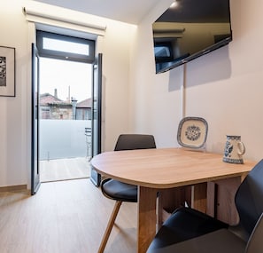 Enjoy a meal at the round table, with a flat-screen TV above and a sliding door leading to an outdoor area with a view.