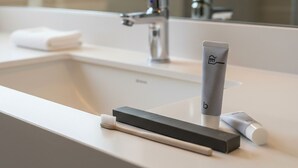 A modern bathroom with a white sink, a mirror, and a toothbrush holder.