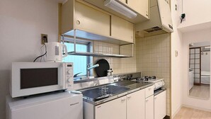 A compact kitchen with white cabinetry, a microwave, a stove, and a sink.