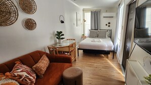Habitació d'hotel senzilla amb llit, sofà, taula petita i televisió.