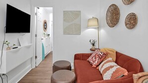 Un saló modern amb televisió plana, un sofà vermell, una làmpada de peu i decoració mural.
