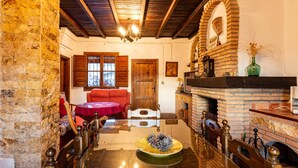 A cozy room with a wooden table, a fireplace, and a stone wall. - Complex of 2 houses with swimming pool, (Melegís)