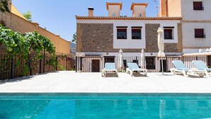 A pool area with lounge chairs and a building with a stone facade. - Complex of 2 houses with swimming pool, (Melegís)