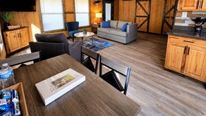Amplia sala de estar con techo de madera, un sofá, una mesa de centro y una mesa de comedor con sillas.