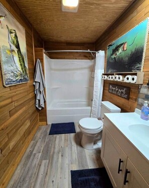A wooden cabin bathroom with a shower, toilet, and sink.