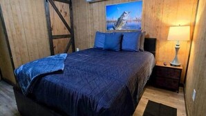 Un dormitorio con una cama, una mesita de noche, una lámpara, un cuadro y una lámpara en el techo.