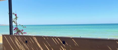 A covered outdoor seating area with a view of the ocean.
