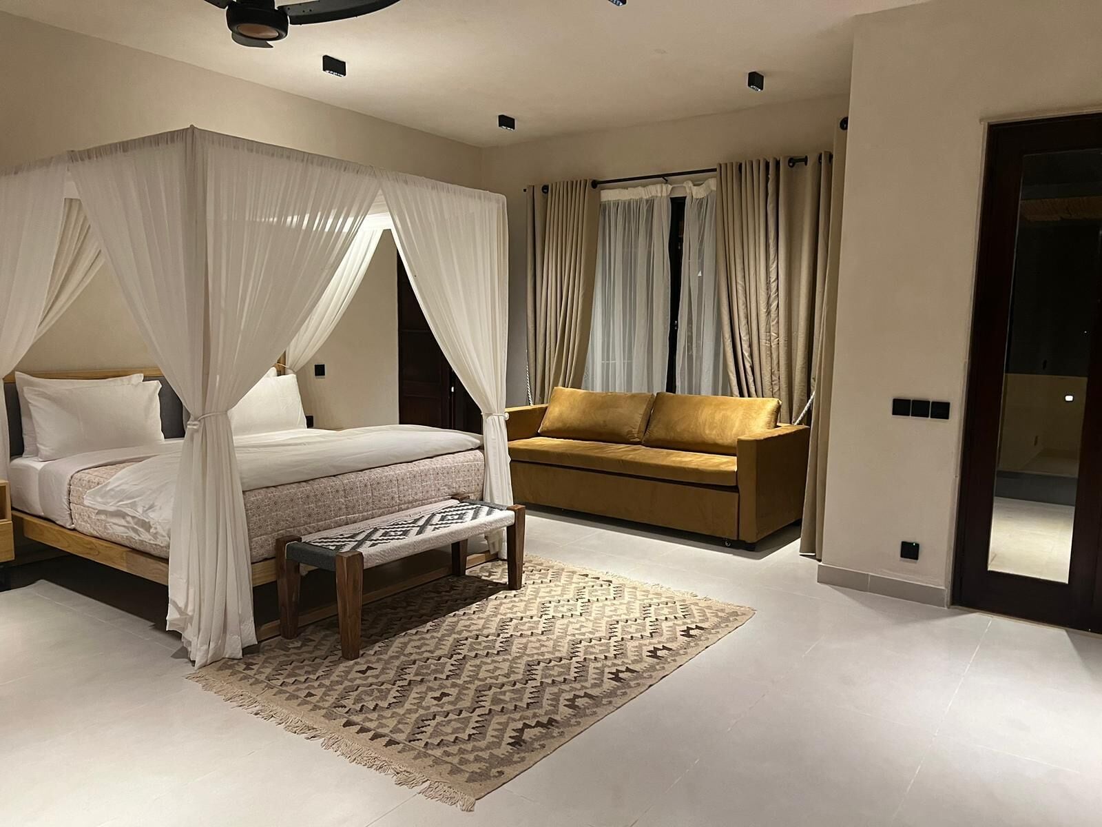 Une chambre à coucher avec un lit à baldaquin, un canapé et un tapis à motifs.