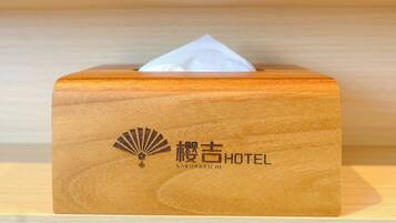 A wooden tissue box with a fan and hotel name on it.