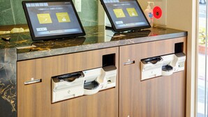 A reception desk with two digital kiosks displaying information. - SAKURAKICHI HOTEL (Izumisano)