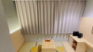 A small, compact room with a bed, a wooden table, two round chairs, a coffee machine, and a shelf with storage. - SAKURAKICHI HOTEL (Izumisano)