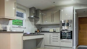 A compact kitchen with a built-in oven, microwave, and a window overlooking a green outdoor area.