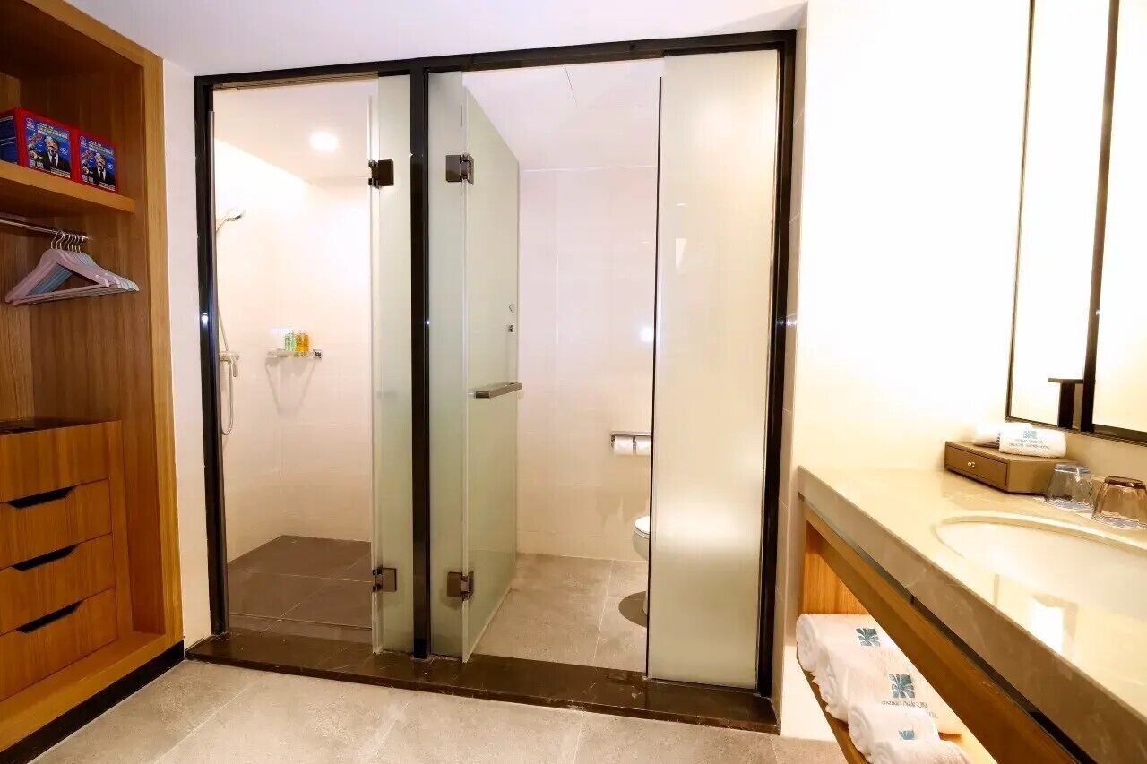 A modern bathroom with a glass shower enclosure, a wooden vanity, and a large mirror.