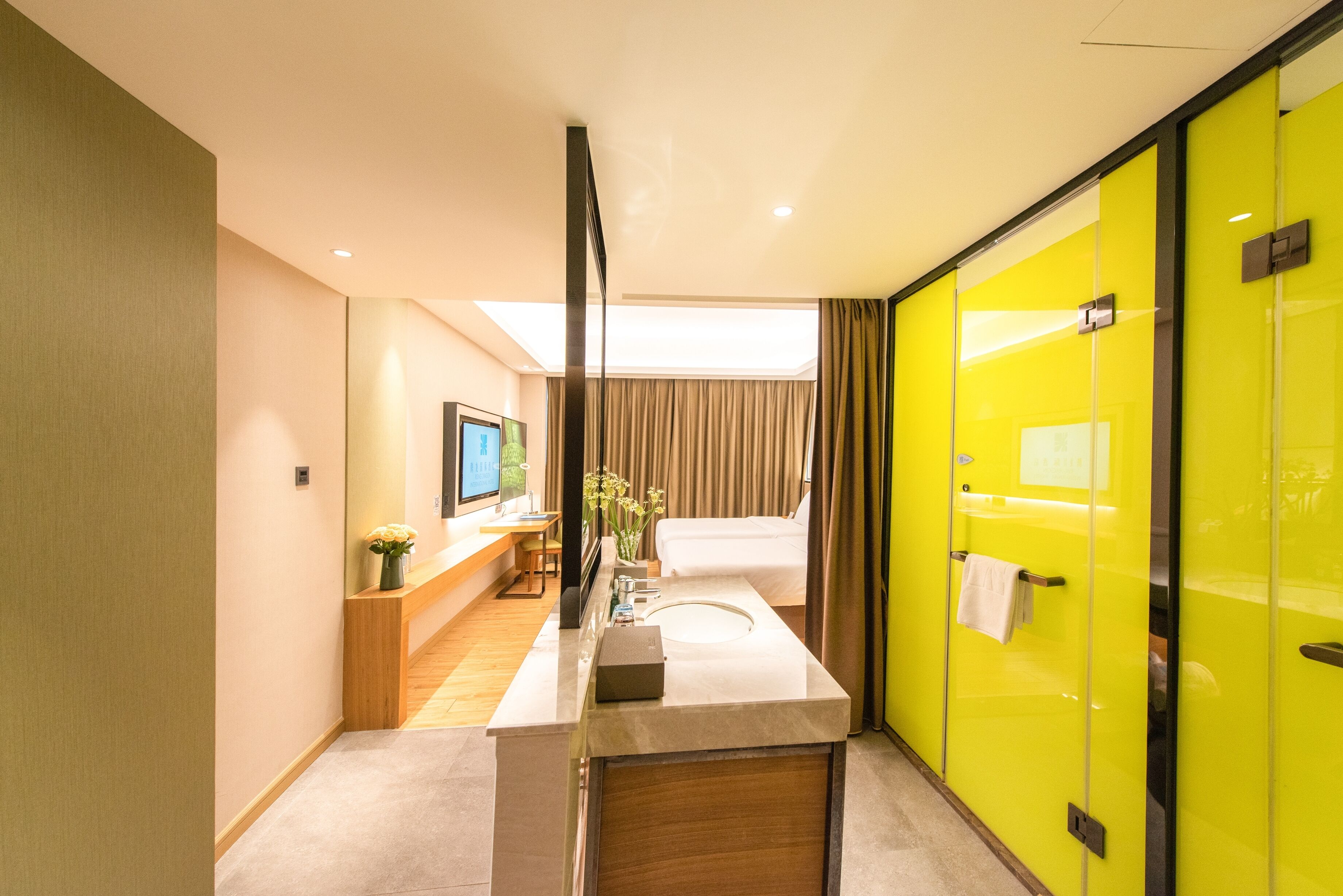 A modern hotel bathroom with a large mirror, a sink, and a shower area.