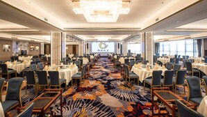 A large banquet hall with rows of tables and chairs, a central chandelier, and a carpeted floor. - Rising Dragon International Hotel (Dongguan)