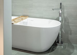 Ein modernes Badezimmer mit freistehender Badewanne, einer Duschkabine und einer Holzablage auf dem Boden.