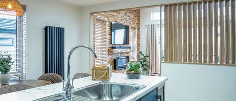 A modern kitchen with a marble countertop, stainless steel sink, and blue cabinets.