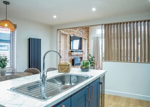 A modern kitchen with a marble countertop, stainless steel sink, and blue cabinets.